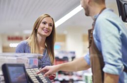 Woman next to cash register talking with sales clerk