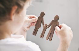 The little child looking on the wooden figures of mom, dad and child in his hands. Concept of the child dreaming about family