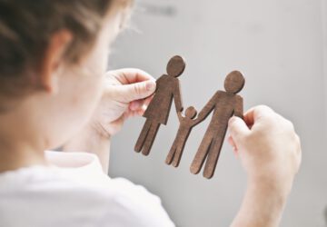 The little child looking on the wooden figures of mom, dad and child in his hands. Concept of the child dreaming about family